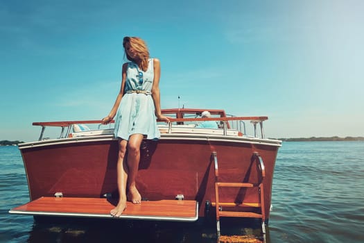 Away from the city and onto the soothing seas. an attractive young woman spending the day on her private yacht.