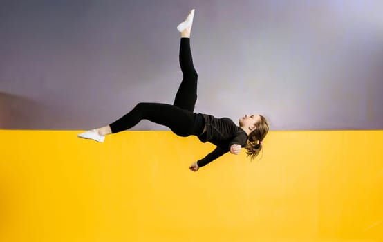 Young woman amateur acrobatic athlete jumping and exercising on a trampoline indoors