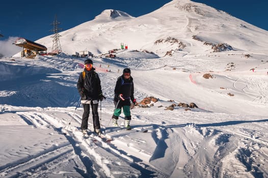 pair of skiers standing on skis side by side in a helmet and goggles getting ready for the descent. The concept of winter friendly outdoor recreation in the mountains