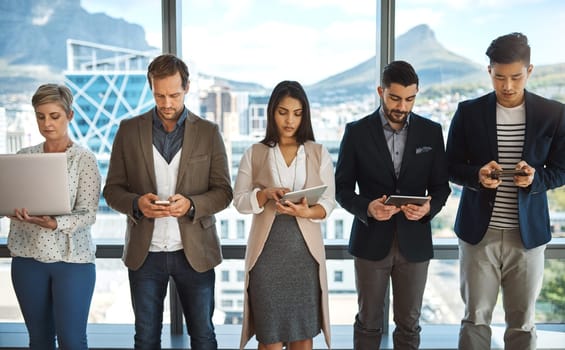 We have a string of connections in the business world. a diverse group of businesspeople using their digital devices in an office.