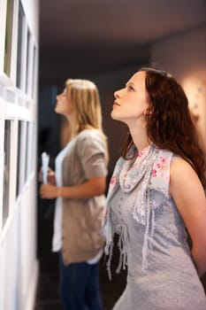 Taking in a century of art. Shot of a young woman looking at paintings in a gallery.