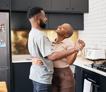 Dance, love and happy black couple in the kitchen having fun together in their new modern home. Happiness, smile and young African man and woman dancing for romantic or intimate moment in their house