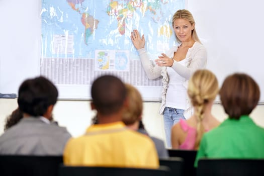 she teaches them well. A geography teacher showing her classroom a map of the world.