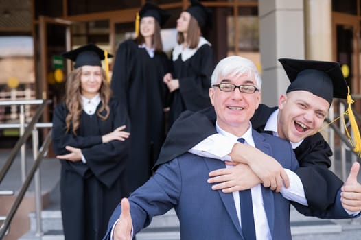 Father and son embrace at graduation. Parent congratulates university graduate