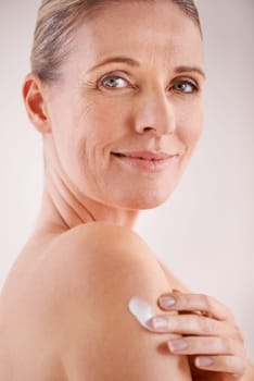 Keeping her skin happy. Studio portrait of a beautiful mature woman applying moisturizing lotion to her skin.