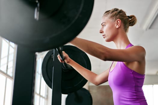 Prove them wrong. a young woman working out with weights at the gym.