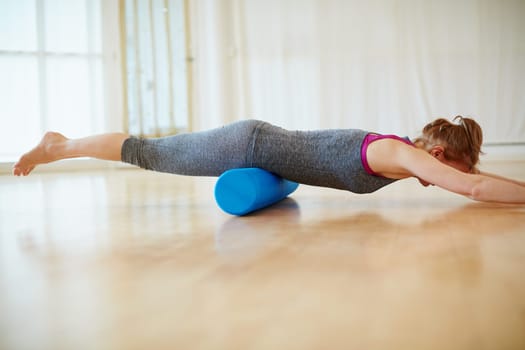 Doing some roller foam exercises to strengthen her muscles. a woman doing roller foam exercises during a yoga workout.