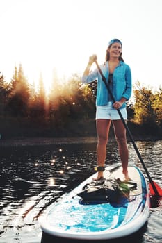 I should do this more often. a young woman paddle boarding on a lake.