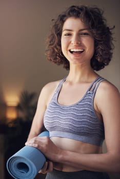 I didnt choose the yoga life, it chose me. Cropped portrait of an attractive young woman standing alone and holding her yoga mat before an indoor yoga session