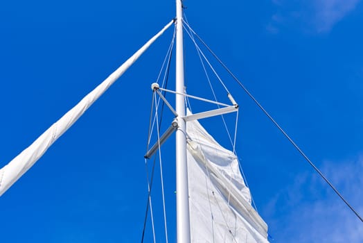 Raising the sail on a yacht. Young man captan lifting the sail of catamaran yacht during cruising