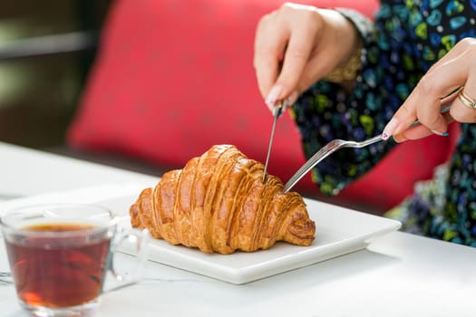Croissant on a white porcelain plate with tea on the side