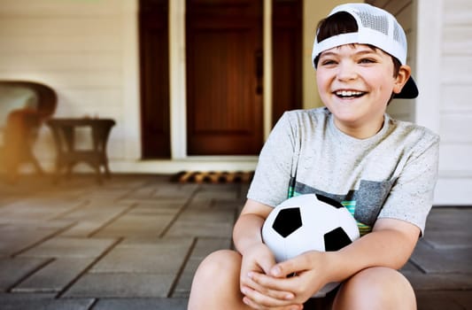 He looks forward to soccer practice. a little boy sitting on the porch with his soccer ball.