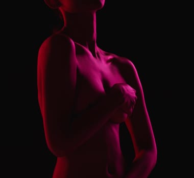 Nude, sexy and naked woman body covering boobs feeling sensual isolated in a dark studio background for sexual desire. Seduction, art and skin by erotic female model with hands on breasts or chest