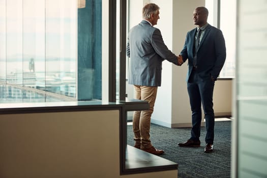 Double the resources, double the success. Full lengths shot of two businessmen shaking hands in an office.
