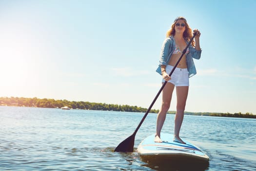 Let me take you on a paddle through my happy place. an attractive young woman paddle boarding on a lake.