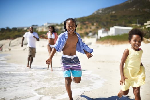 Mom and dad cant catch us. An african-american family enjoying a day at the beach together.