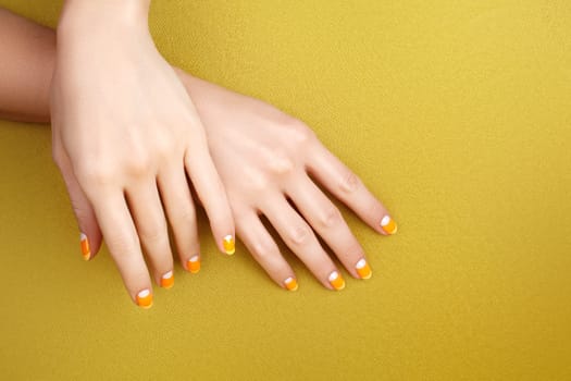 Beautiful Female Hands with bright orange Manicure like Candy Corn. Manicured Nails with Yellow Gel Polish. Halloween Style