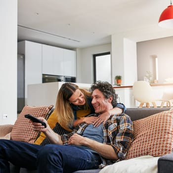 Happy couple, tv and hug to watch movies, news and cable show for media entertainment on lounge sofa. Mature man, woman and relax with television remote, subscription and smile for streaming service.