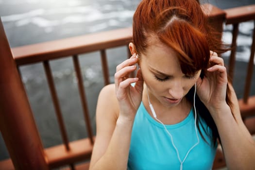 Staying healthy and in shape with the perfect soundtrack. a sporty young woman listening to music while out for a run in the city.