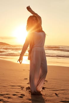Getting lost in the beauty of the day. a young woman standing with her arms outstretched at the beach.