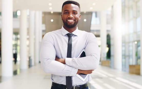 I am not afraid of any work challenges. Cropped portrait of a handsome young businessman standing with his arms folded ad holding a tablet while in the office.