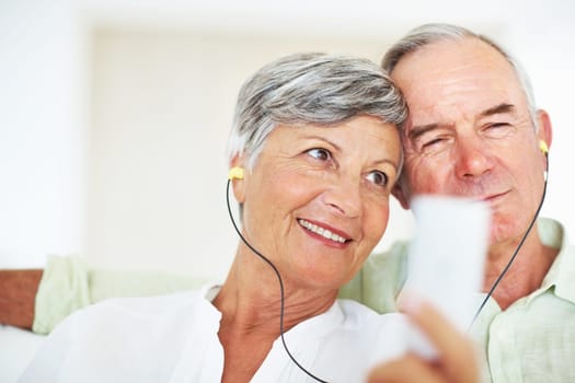 Mature couple listening music together. Closeup of happy mature couple listening music together at home.
