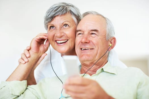 Smiling mature man and woman listening music. Smiling mature man and woman listening music while relaxing at home.
