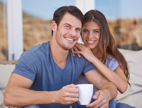 Shot of an affectionate young couple relaxing on the patio with coffee.