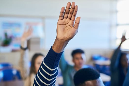 He knows all the answers. an unrecognizable varsity student raising his hand in class.