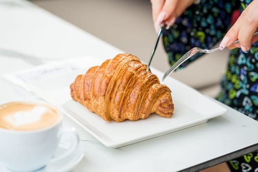 Croissant on a white porcelain plate with coffee on the side