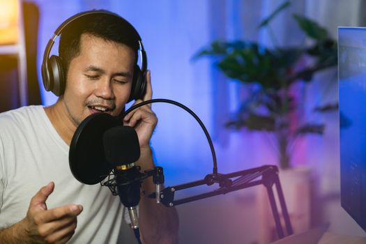 Man singing with headphone recording new song with microphone in the home recording studio