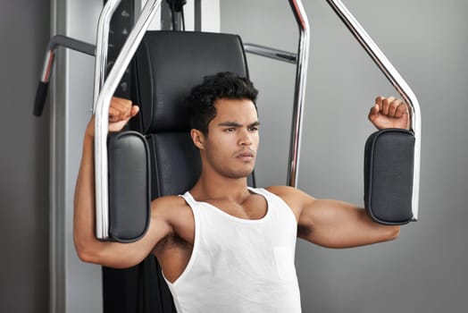 Staying focused and motivated. A young ethnic man exercising in the gym.