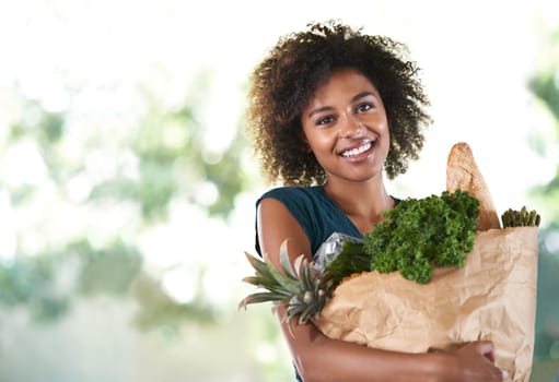 Bag of health. Young girl smiling while holding her groceries - isolated.