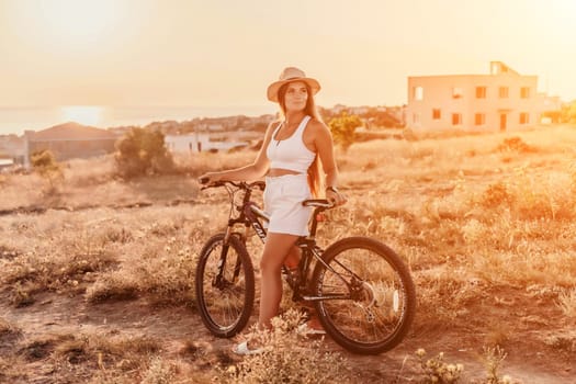 Woman travel bike. Happy woman cyclist sitting on her bike, enjoying the beautiful mountain and sea landscape, signifying the idea of an adventurous bike ride