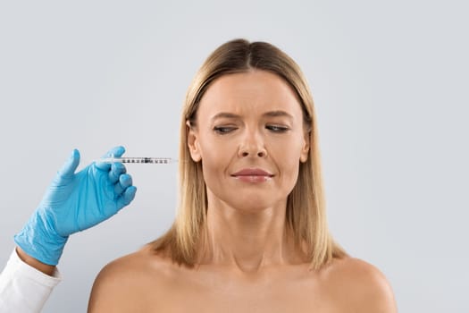 Middle aged lady scared receiving hyaluronic acid injection