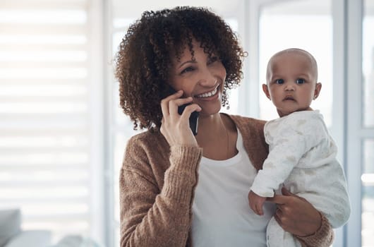 Parenting advice is just a call away. a young woman using a smartphone while carrying her adorable baby girl at home.