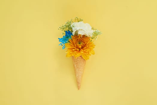 Floral ice cream in a cone in a studio for art, creativity or decoration with fresh and colorful bouquet. Creative, still life and blossom flowers or plants in a dessert isolated by yellow background