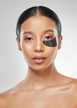 Its skin cell metabolism boosting. Studio portrait of an attractive young woman wearing an under eye patch against a grey background.