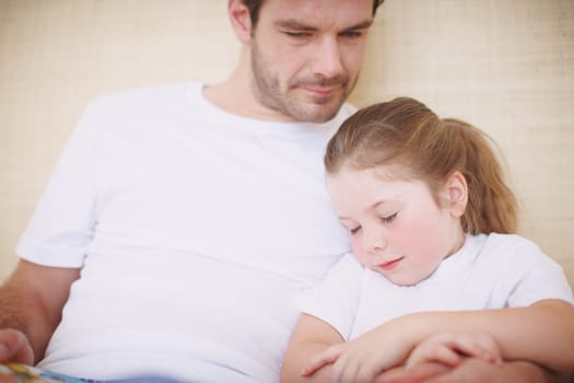 Falling asleep in her fathers arms. a devoted father siting with his young daughter while she falls asleep.
