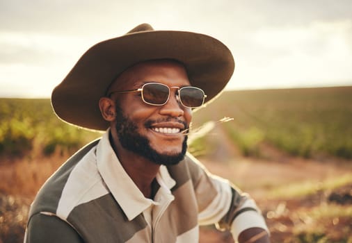 Farm, agriculture and sustainability with a black man farmer outdoor on a grass field or land for organic farming. Agricultural, sustainable and green with a male wearing a hat and sunglasses outside