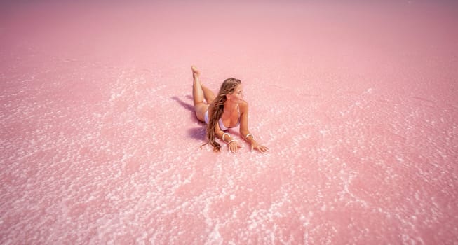 Woman in a pink salt lake. She lies in a white bathing suit. Wanderlust photo for memory