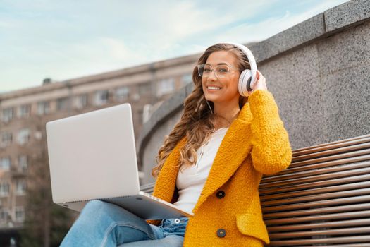 Business Woman Wear Eyeglasses Listen Music Headphone Outdoor Sitting Bench Using Laptop Outdoor