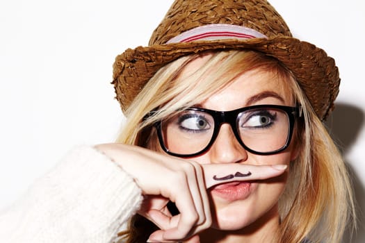 Girl, isolated and hipster pose with mustache on finger, nerd glasses or funny face in studio white background. Young woman, modern fashion and moustache joke or goofy, weird and photobooth