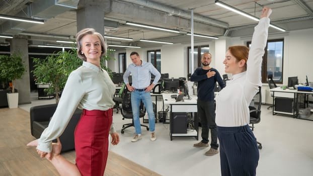 Four office workers warm up during a break. Employees do fitness exercises at the workplace.