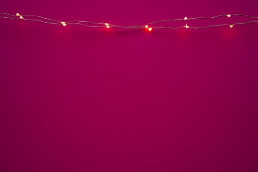 Illuminated garland lights on bright pink background