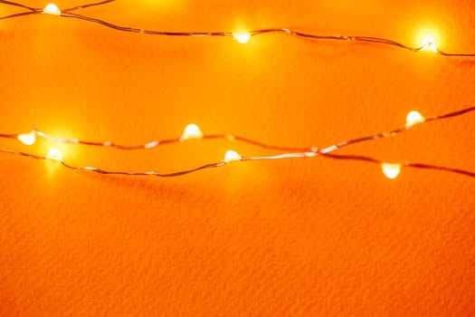 Orange background with illuminated lights of garland