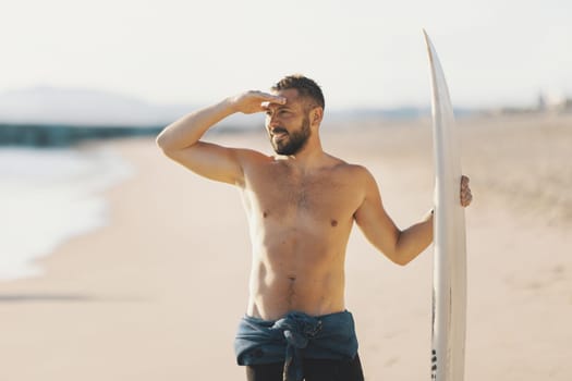A man surfer with naked torso looking in the distance