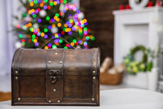 A brown old box in the foreground and a Christmas tree with Christmas lights in the background.