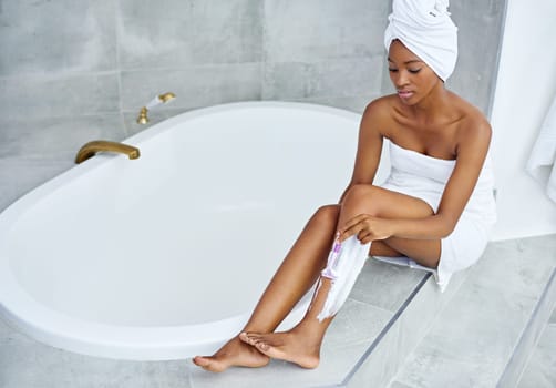 In no time shell have silky smooth legs. High angle shot of a young woman shaving her legs by a bathtub.