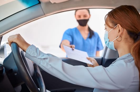 Covid test in car and drive thru, nurse giving patient forms to fill in. Woman in vehicle wearing a mask and taking documents from medical worker. Masks, coronavirus and testing on remote site